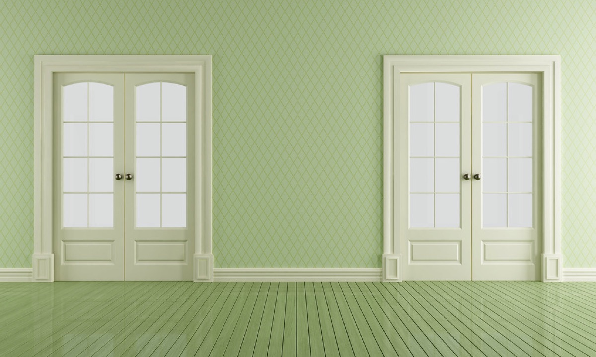 An empty, freshly cleaned room with pale green walls and glass-panel doors