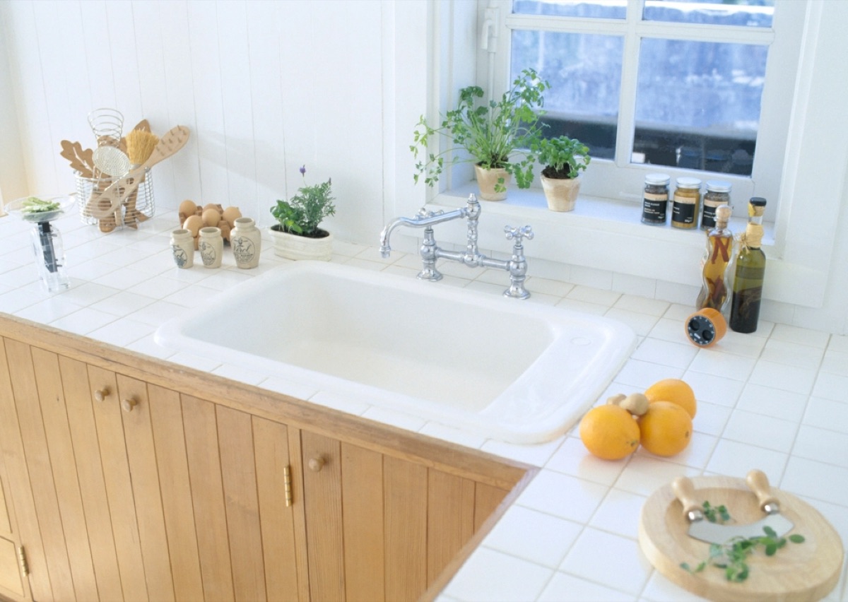 A bright, tidy kitchen with wood cabinets and potted herbs on the windowsill